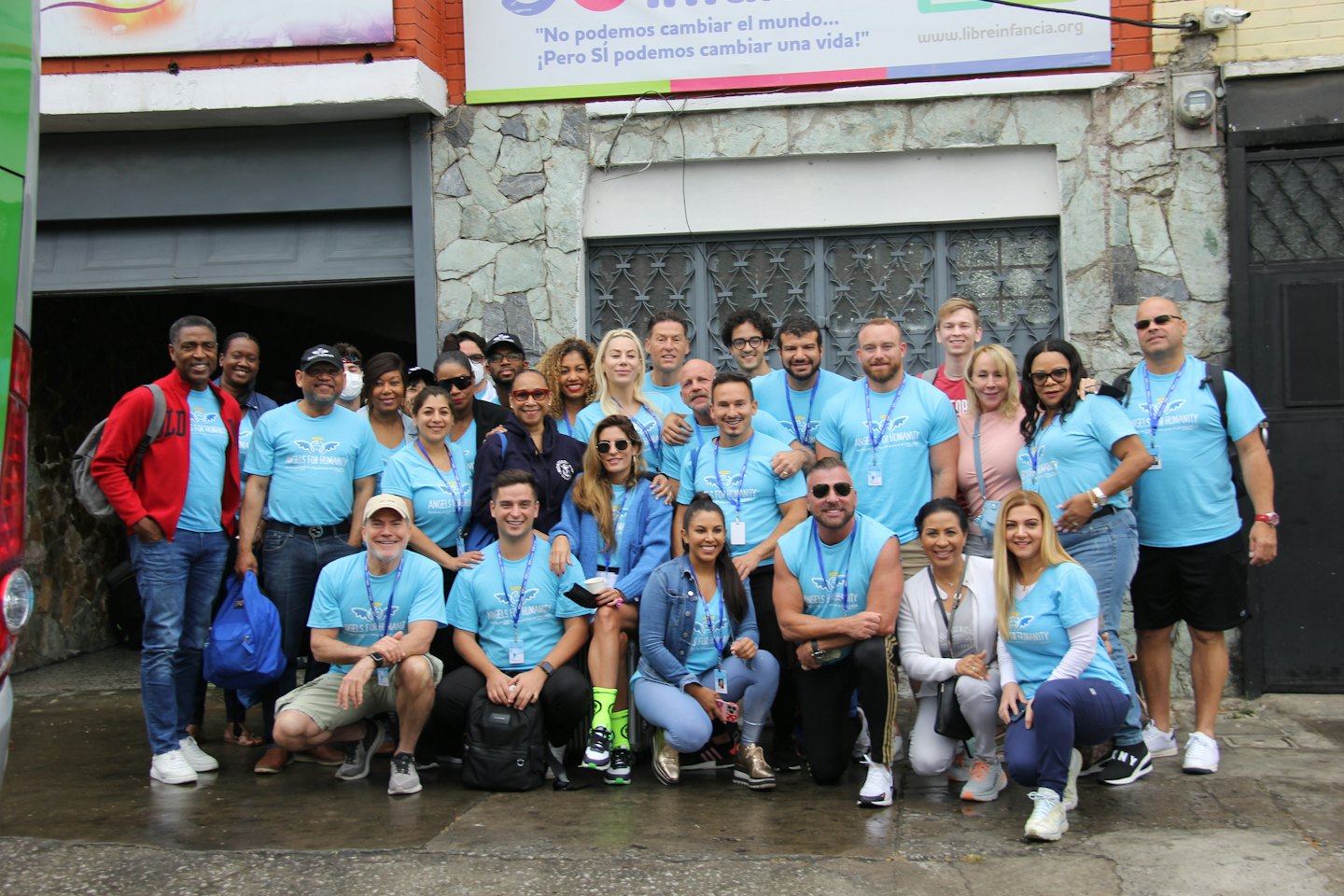 Volunteers in matching blue shirts standing before a stone building.