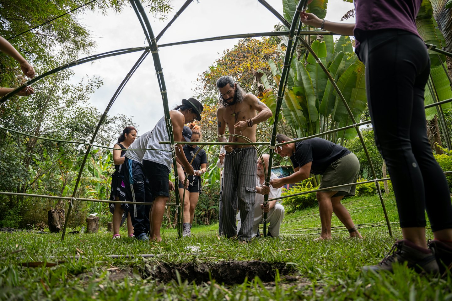 People work together to tie bamboo poles into a dome.